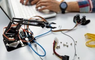 Braccio robotico in costruzione durante una sessione di programmazione su laptop